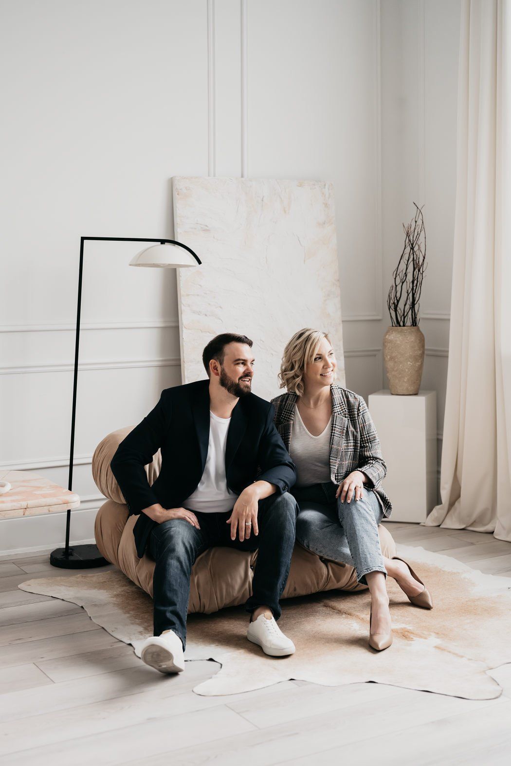 A couple wearing casual outfits as they sit in the middle of a minimalist living room set up