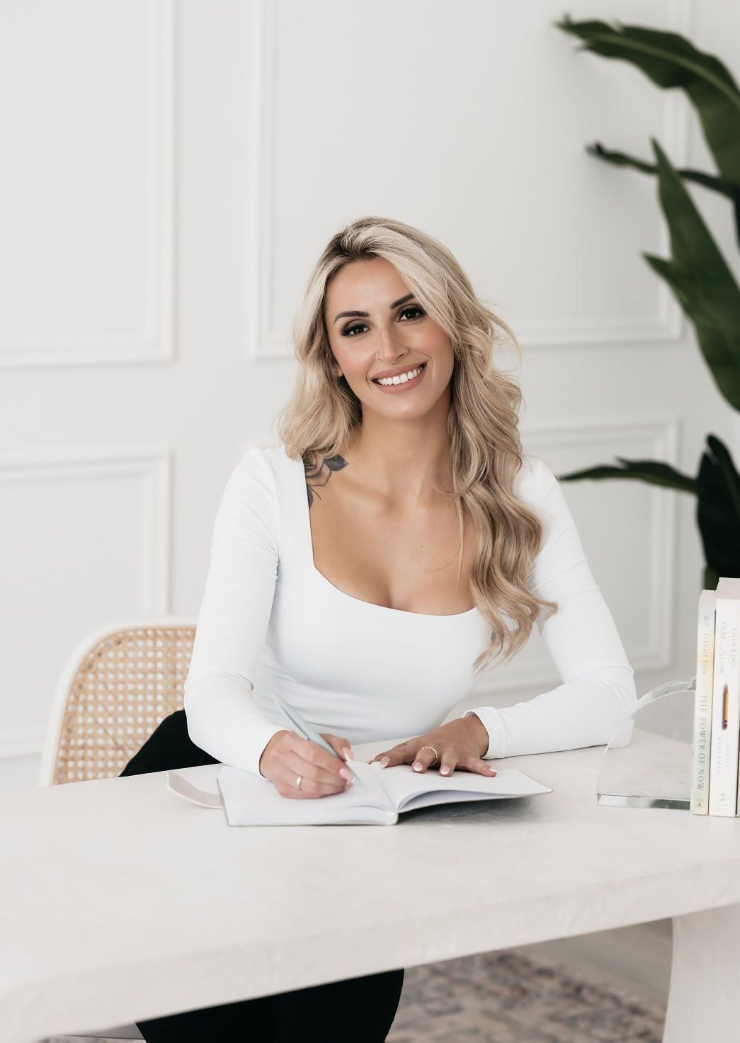A woman is sitting at a desk writing in a notebook.
