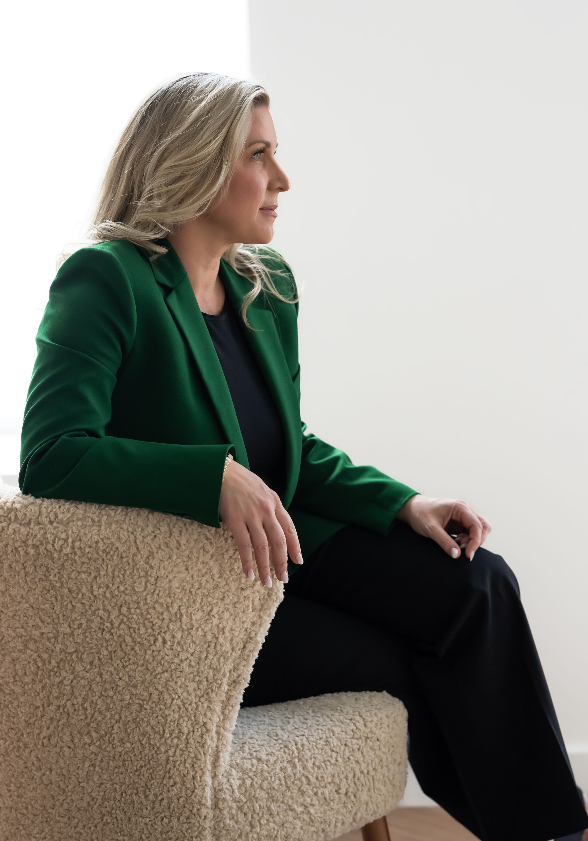 a realtor wearing green suit sitting on a white chair