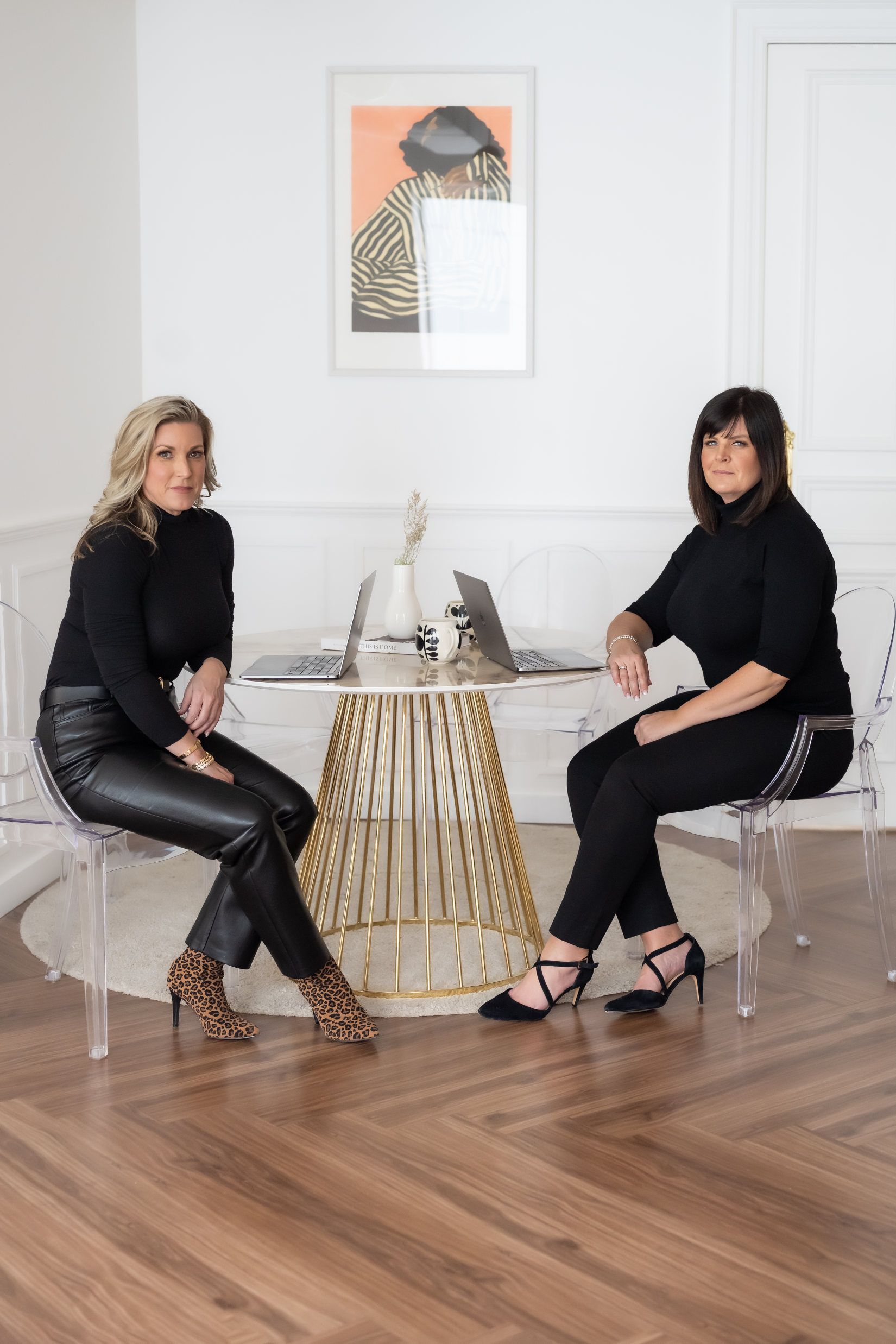 Two women are sitting at a table in a living room.