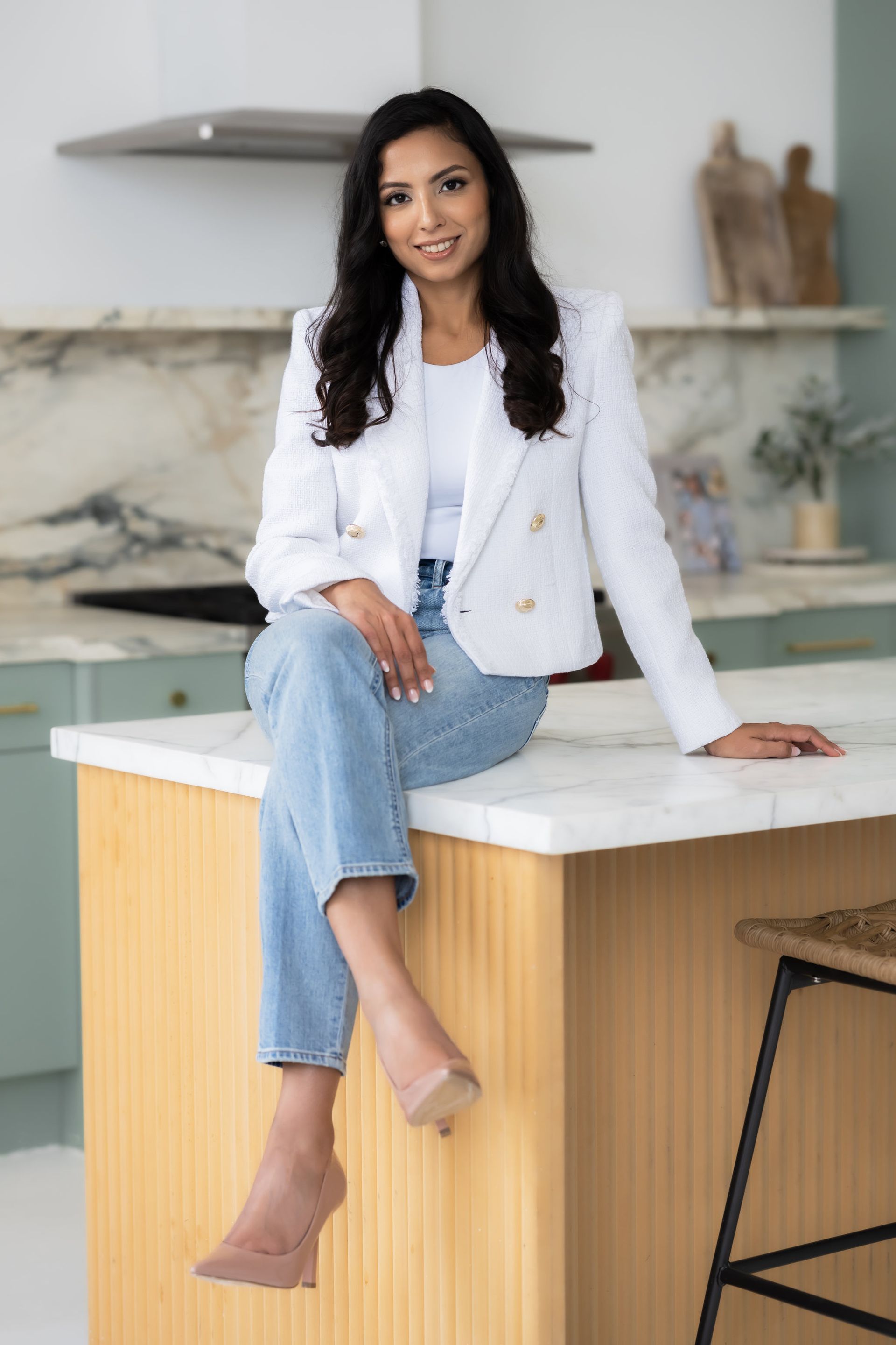 A woman is sitting on a counter in a kitchen.