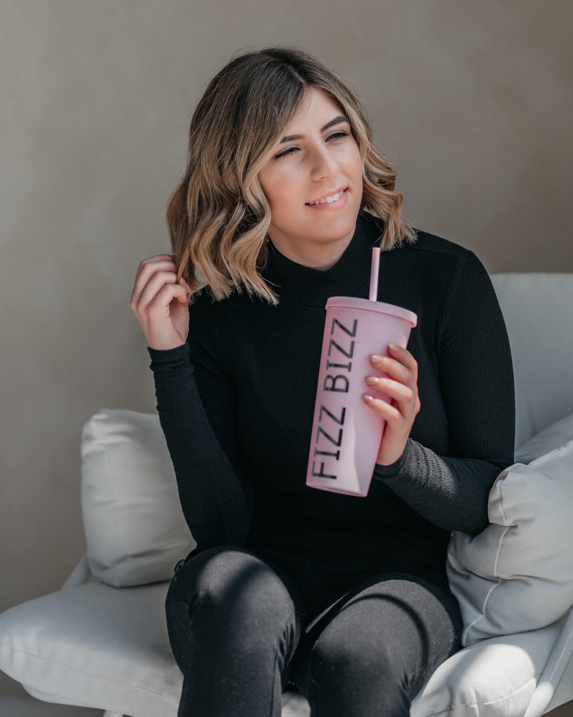Female business owner holding a large cup emblazoned with the name of her company.