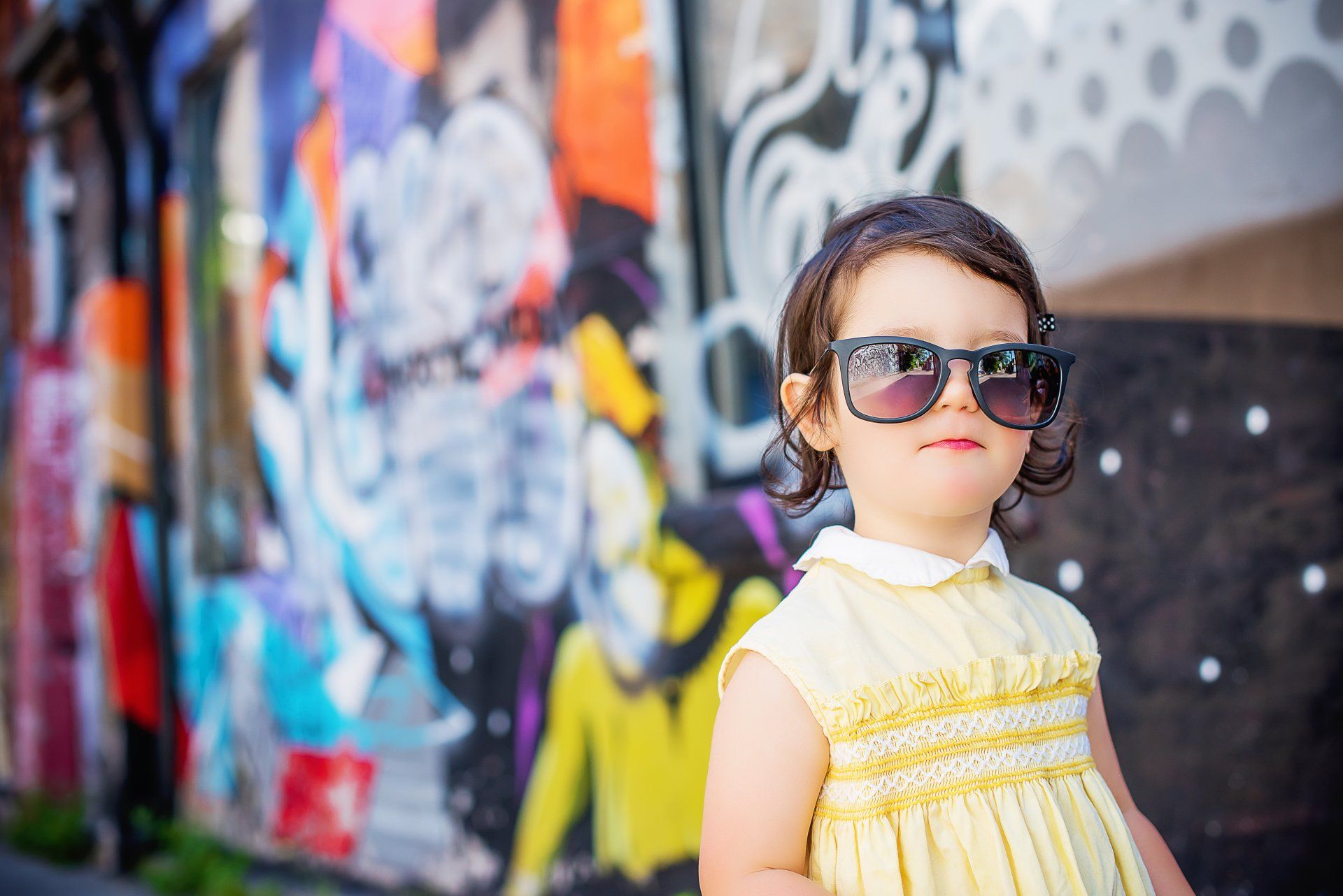 Young girl with glasses in front of graffiti-covered wall | Child photography | Stacey Naglie Toronto