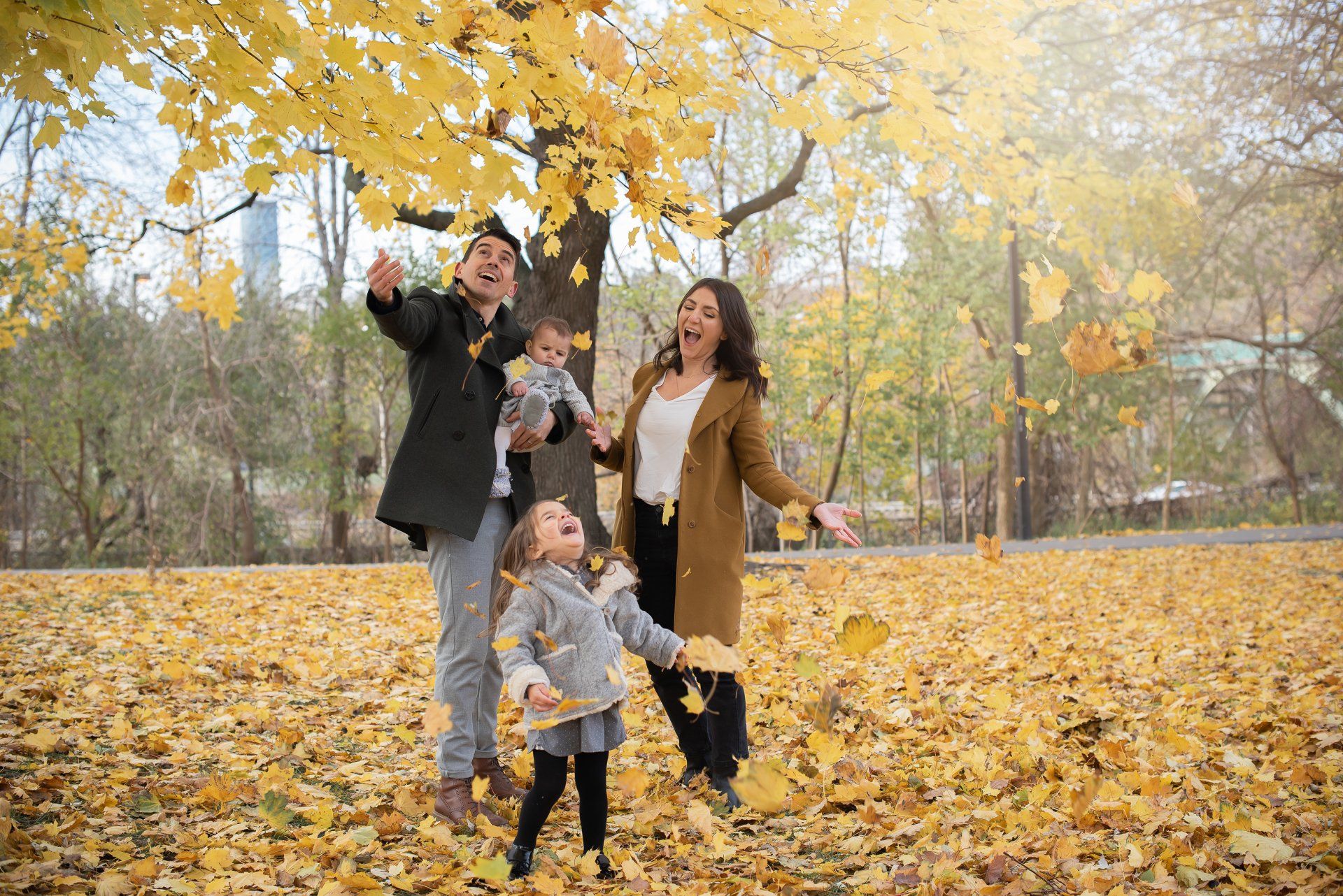 Photo of a family with small children playing in leaves in a park