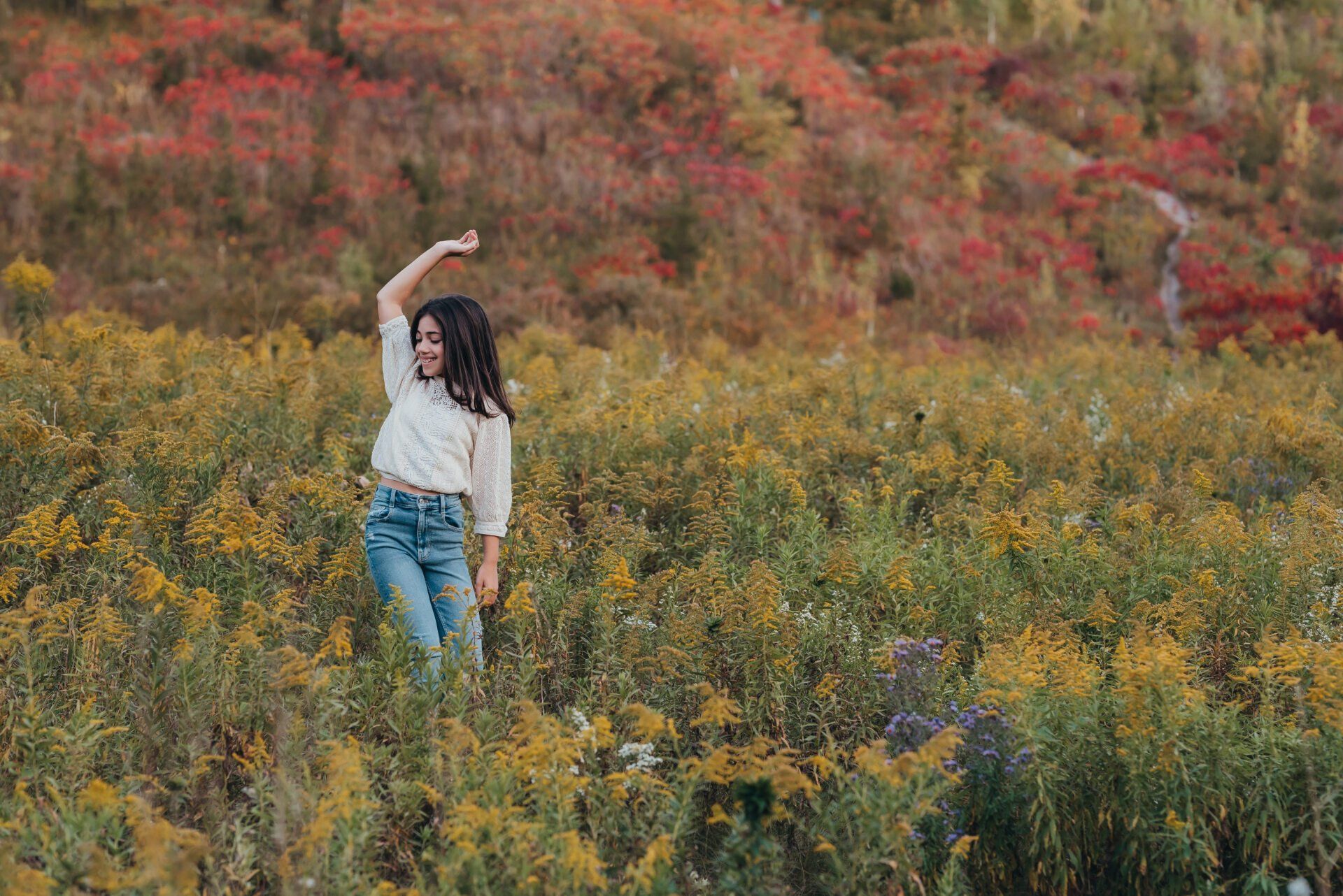 Young girl standing in field of yellow wildflowers for fall photoshoot