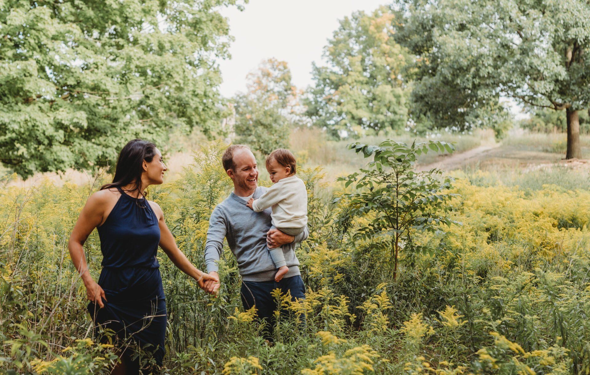 Photo of mother and father holding hands while father holds toddler for family photoshoot gift