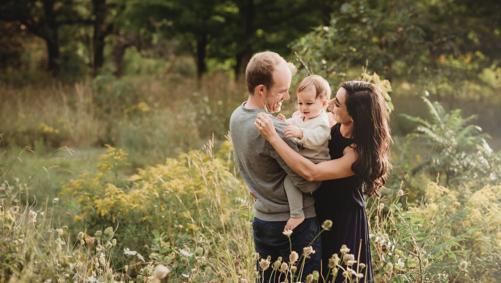 Photo of a father and mother embracing their small toddler in a field of wildflowers for Toronto Gift Idea