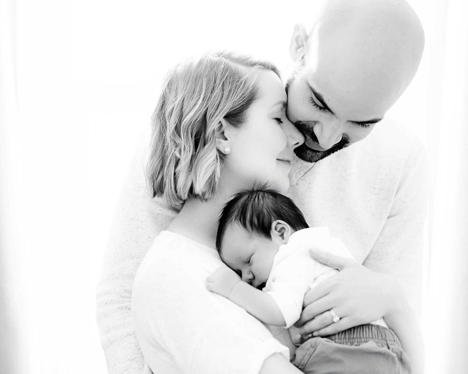 Lifestyle photograph of a man and woman in embrace with newborn baby