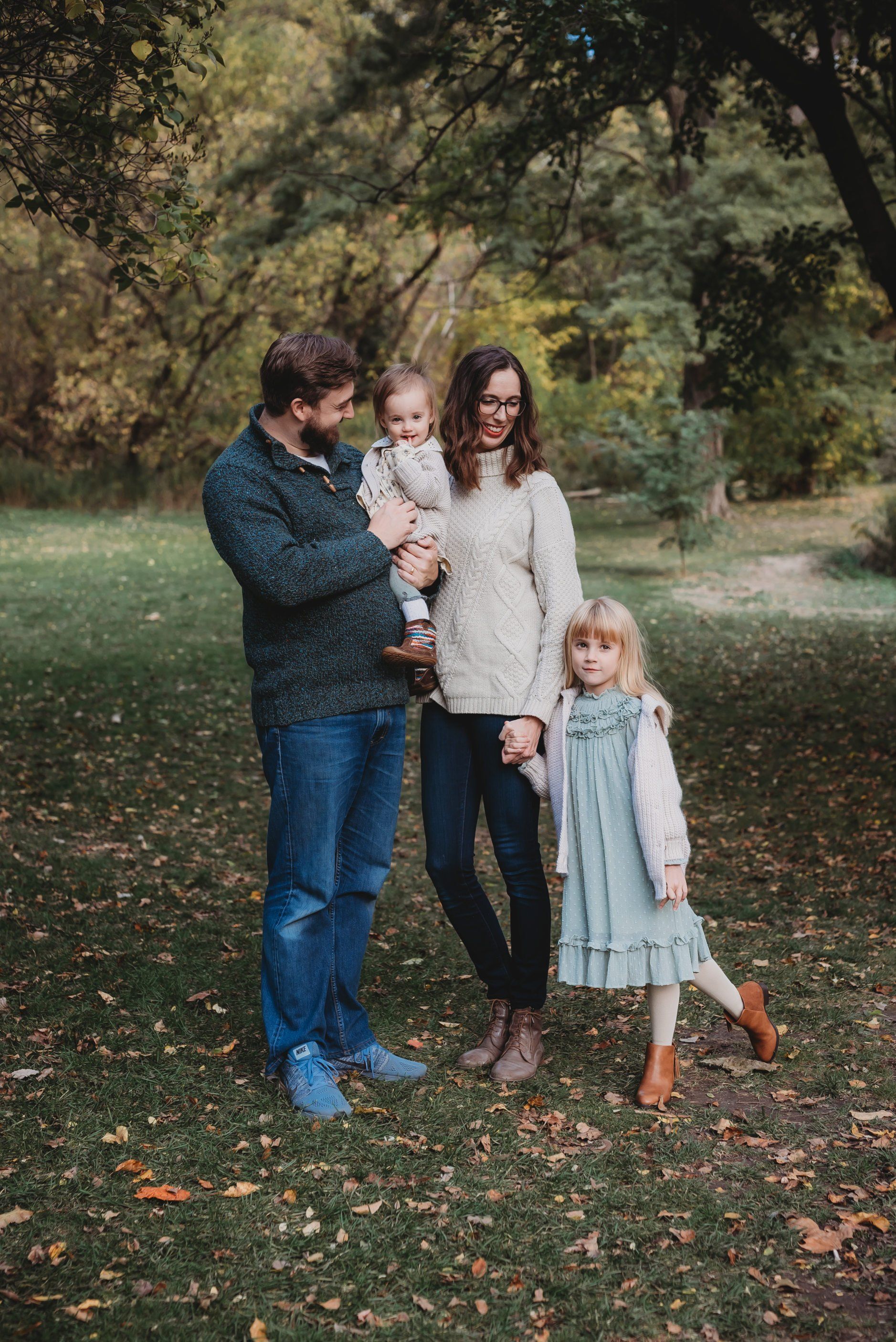 Photo of mom, dad, baby and sister while standing in a field for family photography