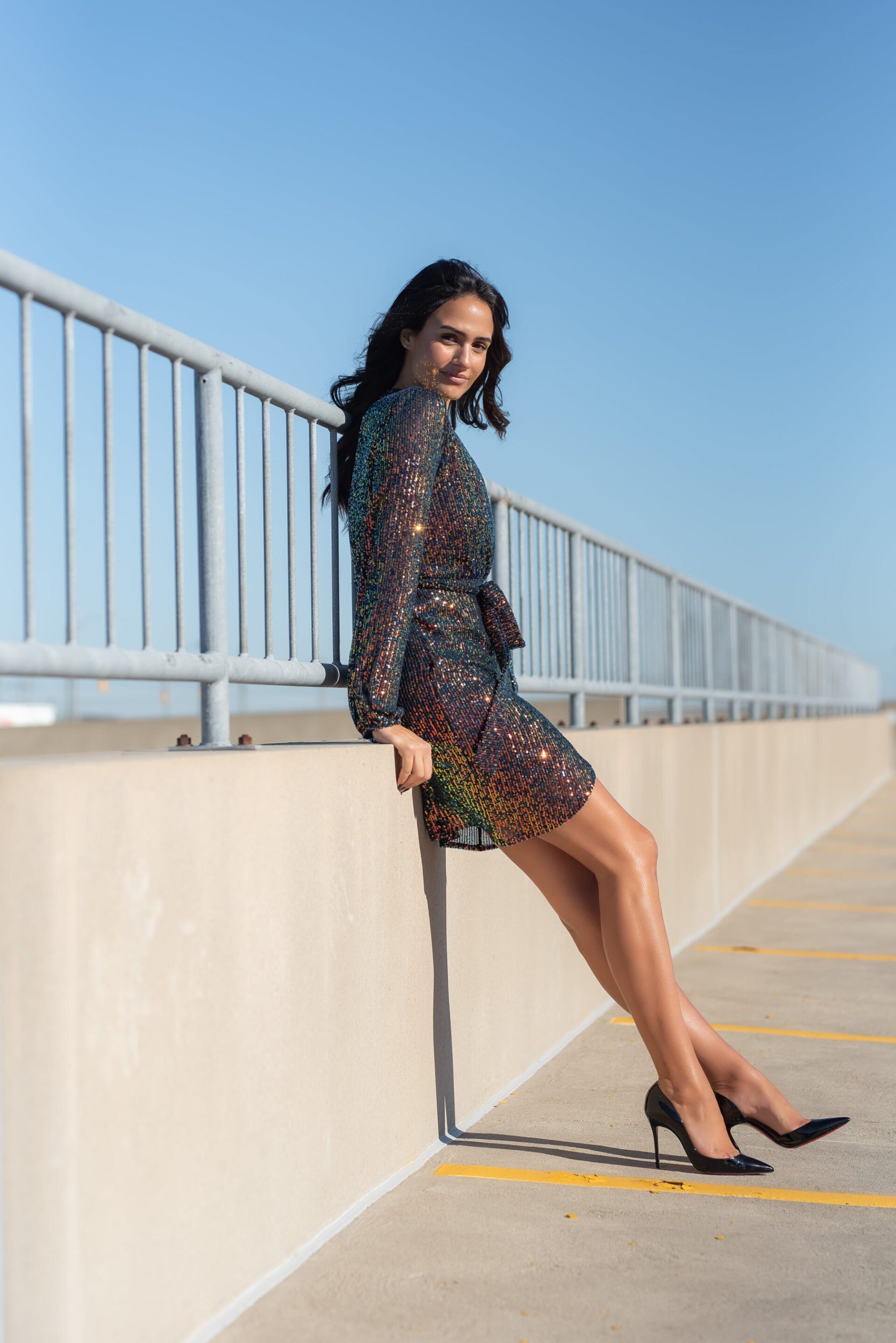 Social influencer Chantel in a sequin dress and black pumps posing by rails