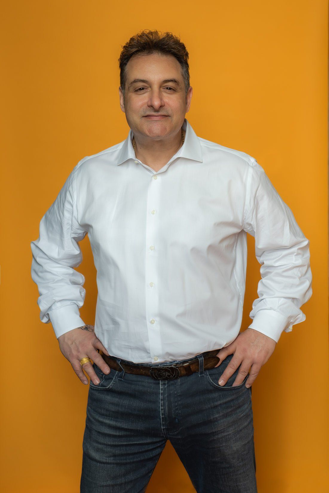 A  business man with hands resting on his waist in LinkedIn headshot photo