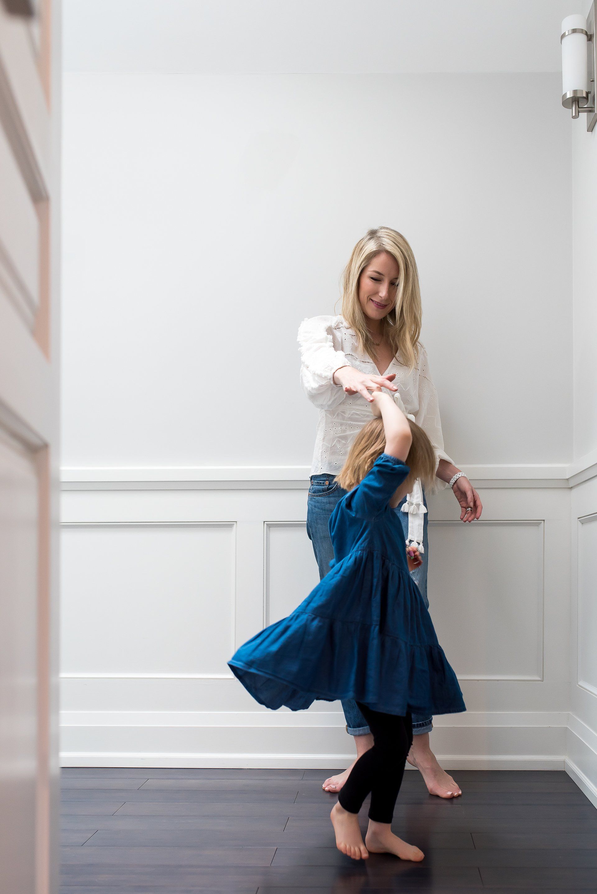 Photo of a mom holding the hand of her daughter as she spins around for family photoshoot gift