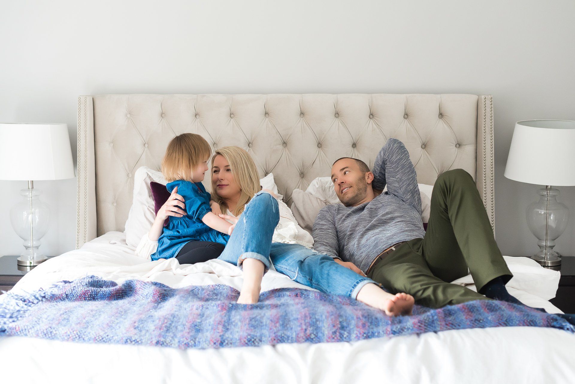 Family photographer Toronto | Stacey Naglie | Man, woman and child lounging on large bed