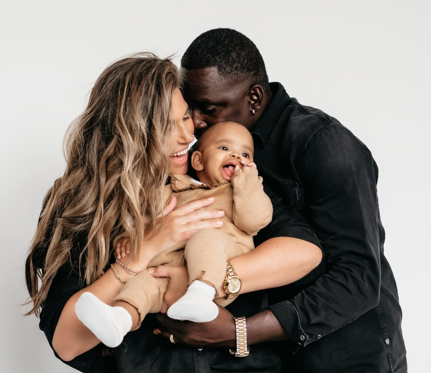 Photo of mom and dad embraced and holding baby for family photography