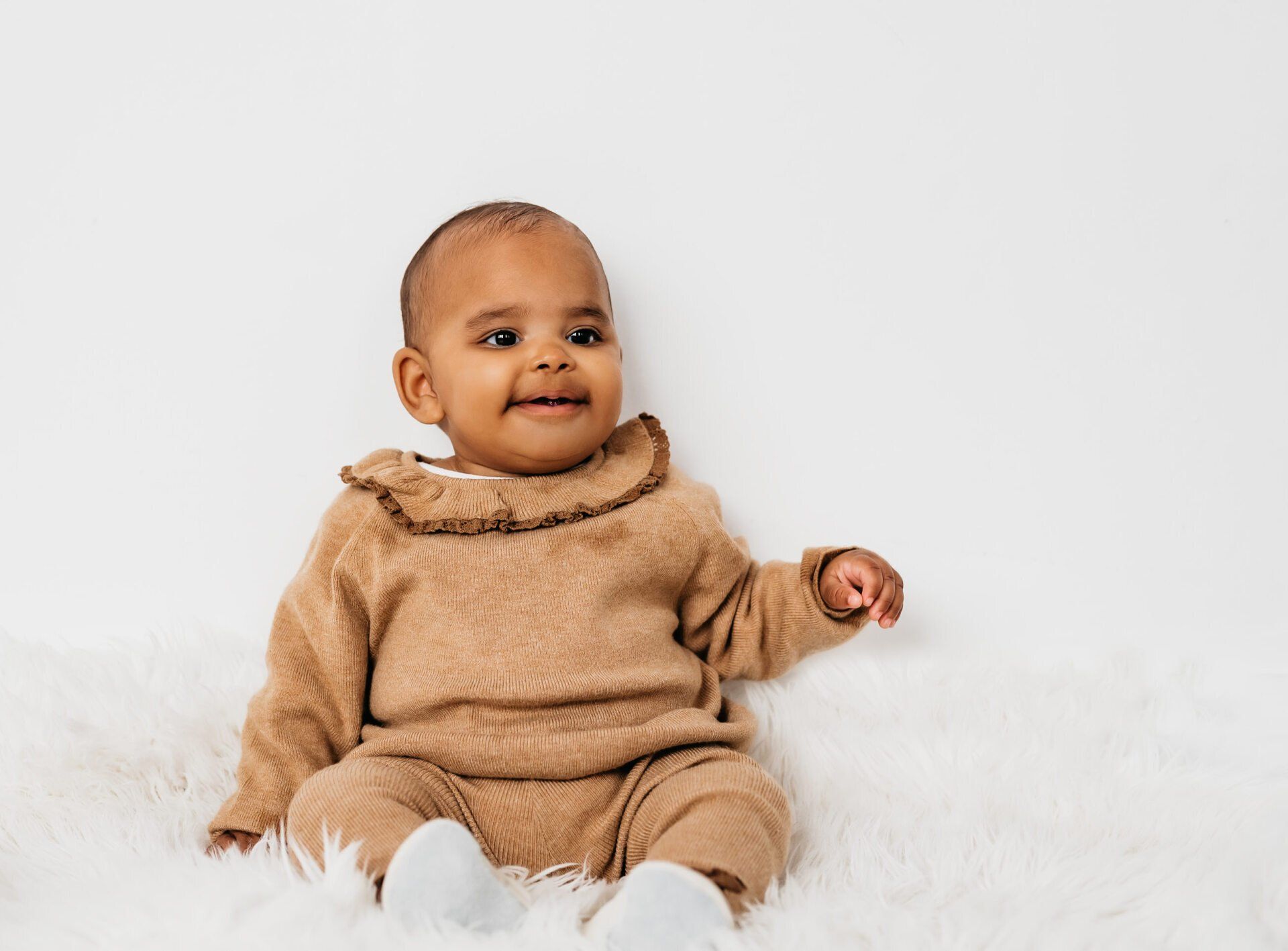 Baby sitting on fluffy white rug for lifestyle photography