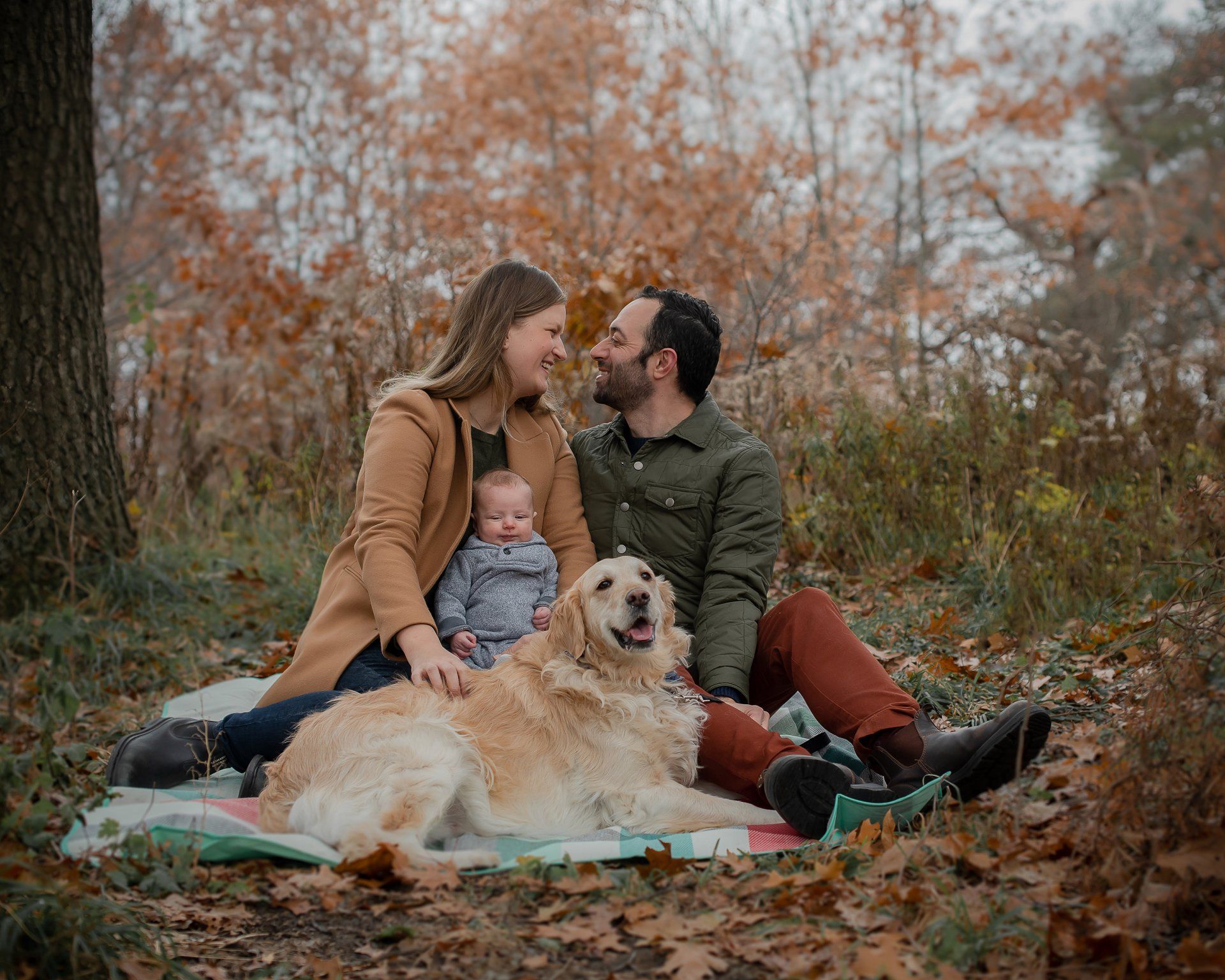 Family photographer Toronto | Stacey Naglie | Man and woman with baby and dog sitting on blanket while outdoors