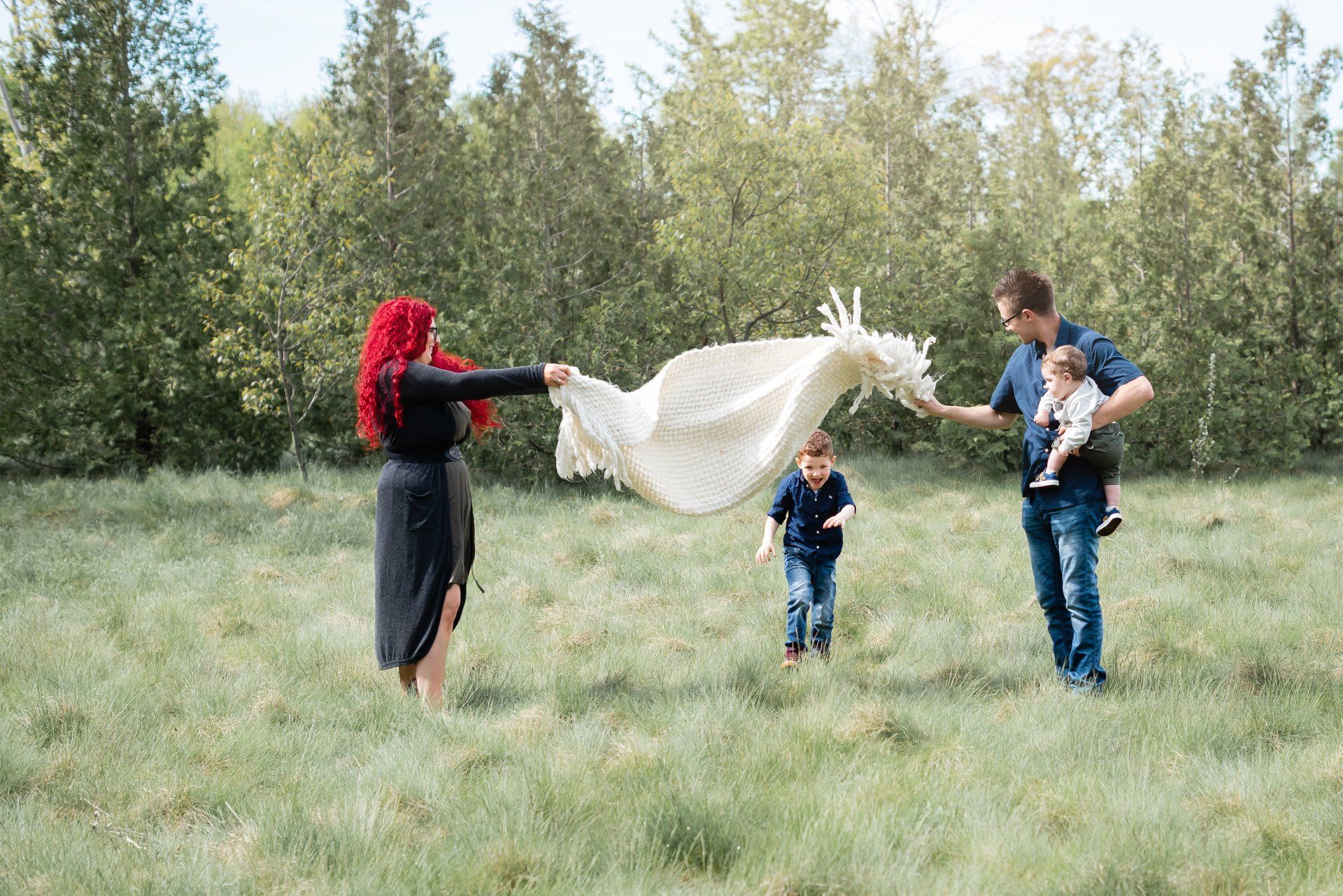 Lifestyle photograph of a family with two children playing in a grassy field