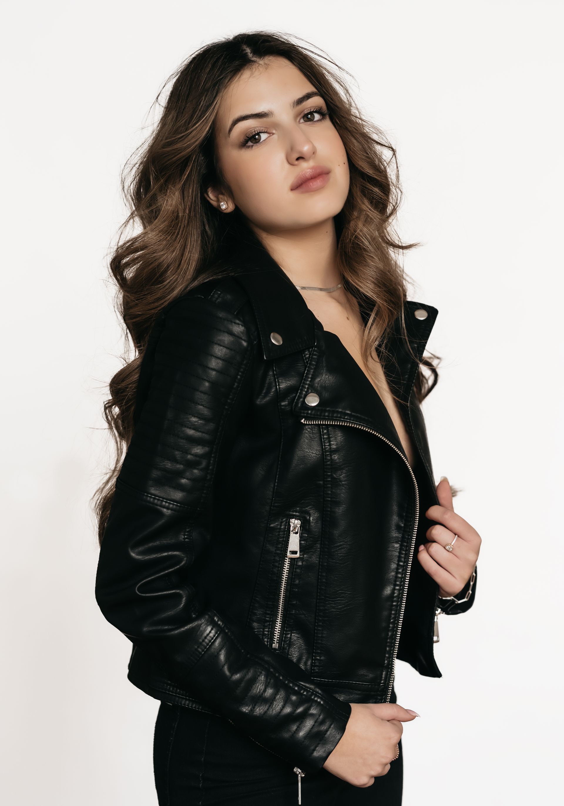 woman with long wavy hair wearing black leather jacket looking at the camera