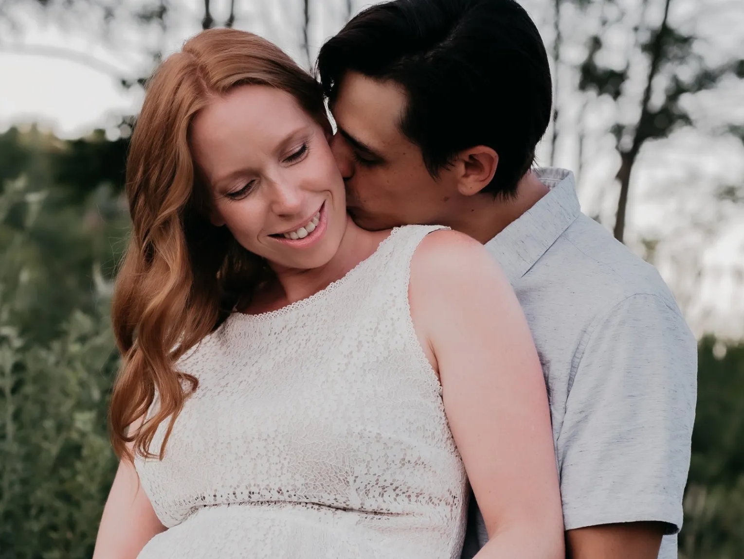 Maternity photograph of pregnant woman embraced by her husband