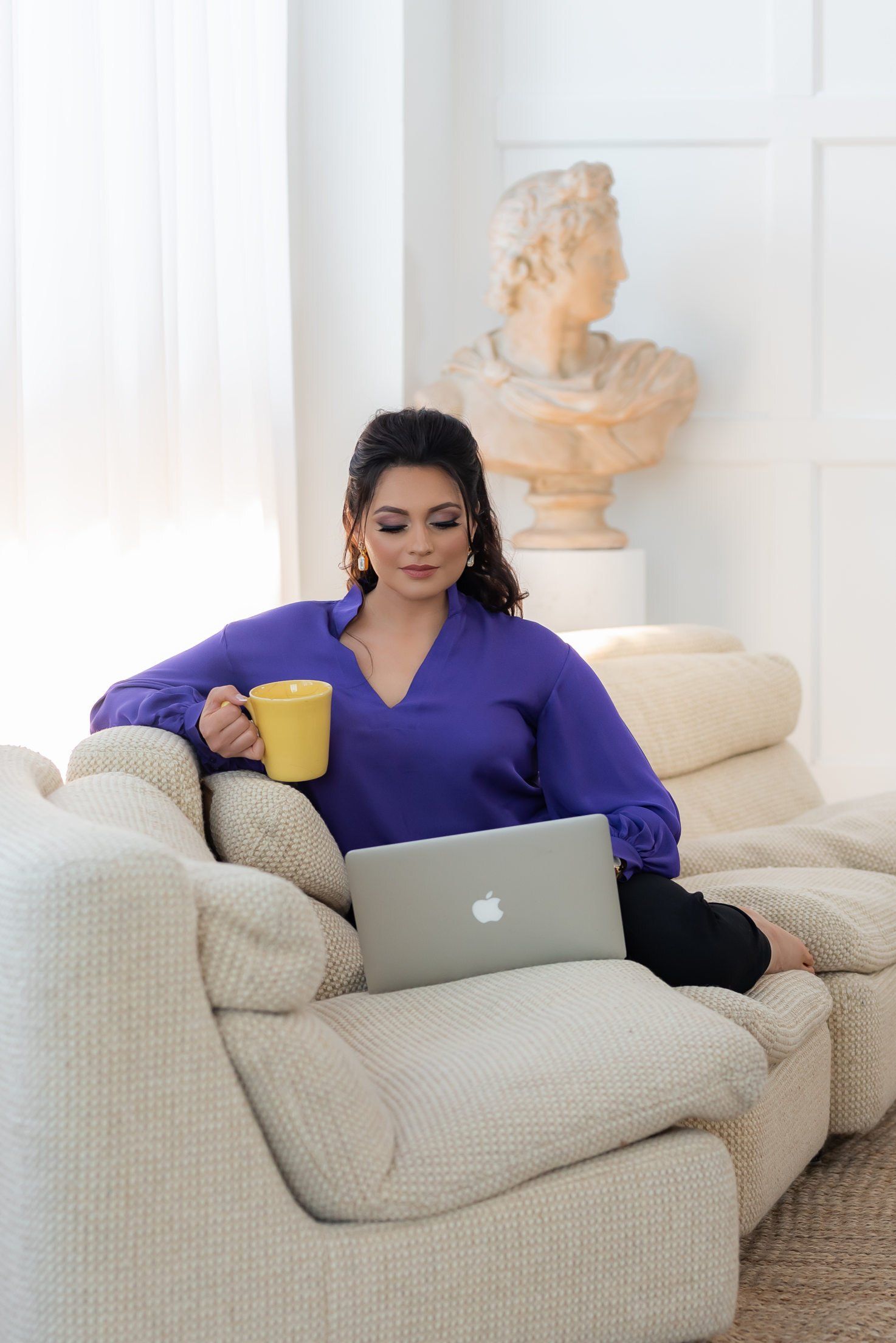 Personal branding photo of female realtor with purple top holding mug and laptop