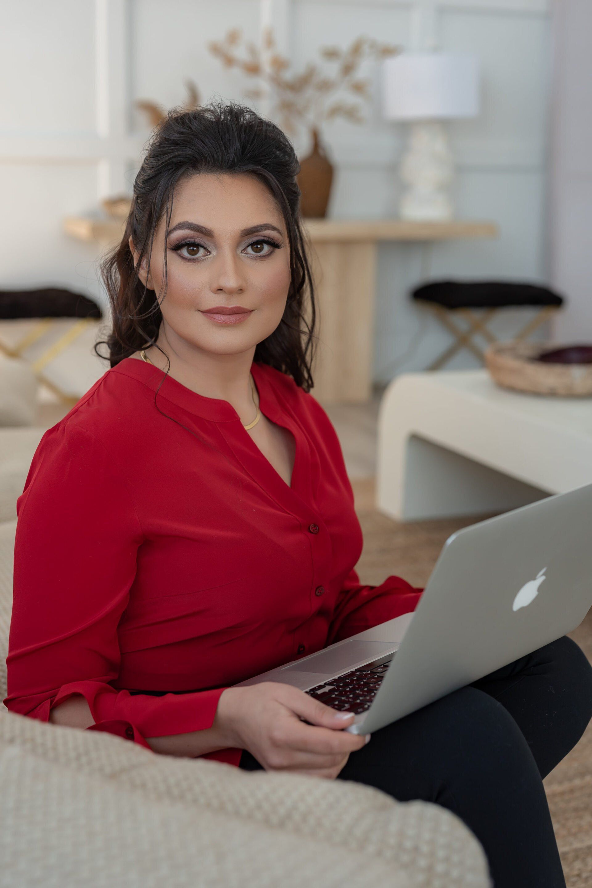 Headshot photo of a female executive wearing a red blouse holding laptop for executive headshots