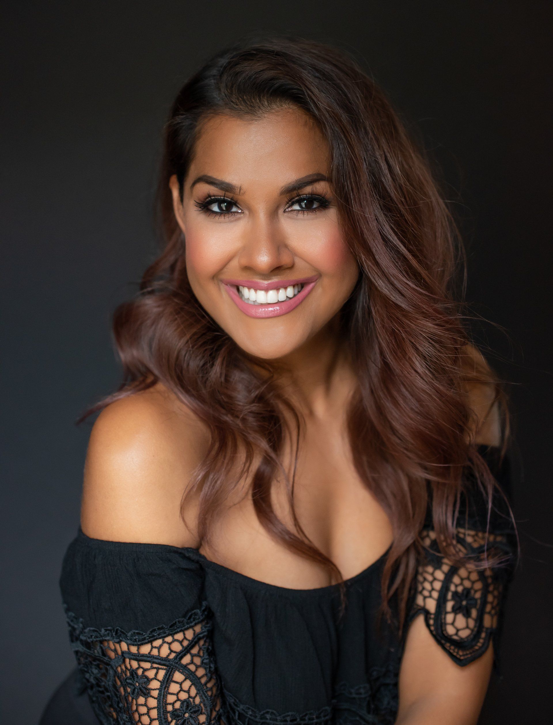 a photo of a smiling woman with brown hair wearing black top