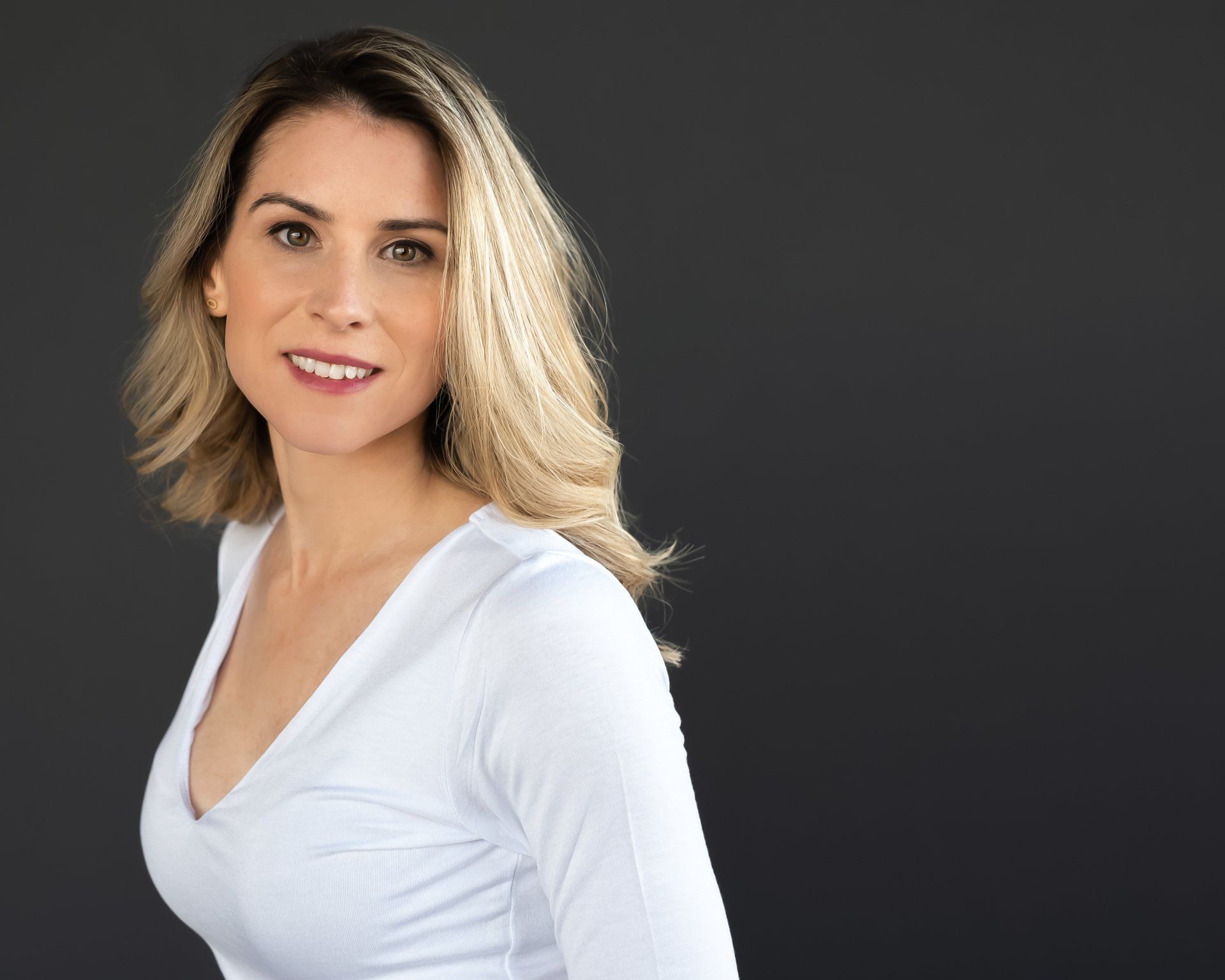 a casual photograph a woman wearing white top with a dark background