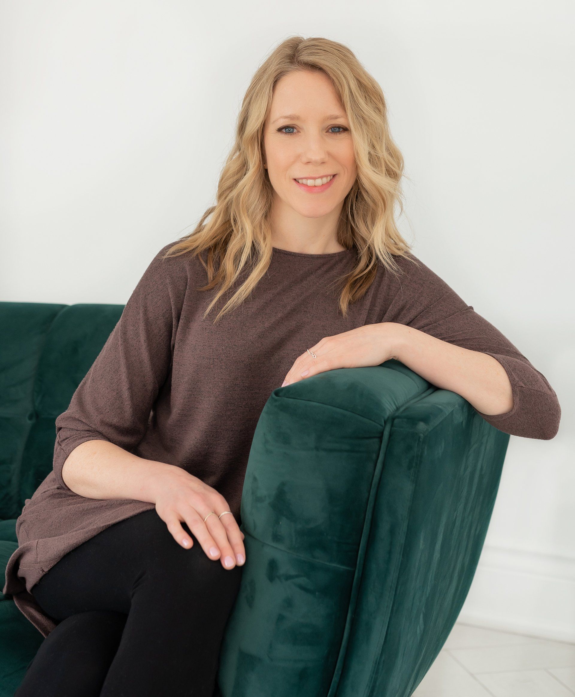 a photo of a woman wearing a brown top sitting on a green couch