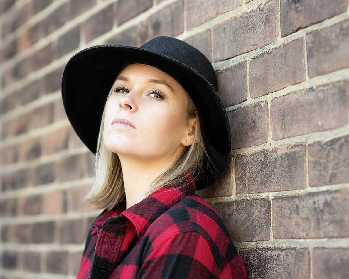 Professional Portrait Photography | Stacey Naglie Toronto  | Woman in plaid shirt and black hat leaning against brick wall