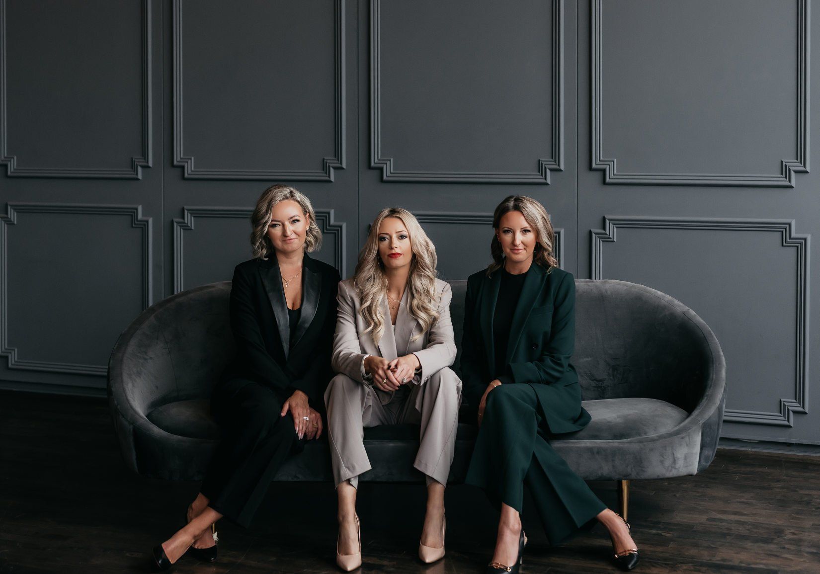 three realtors sitting on a luxurious couch looking at the camera