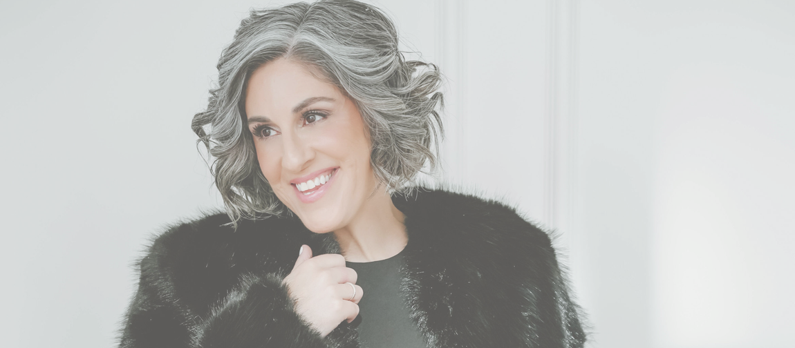 Stacey Naglie smiling in a black fur coat during a photoshoot