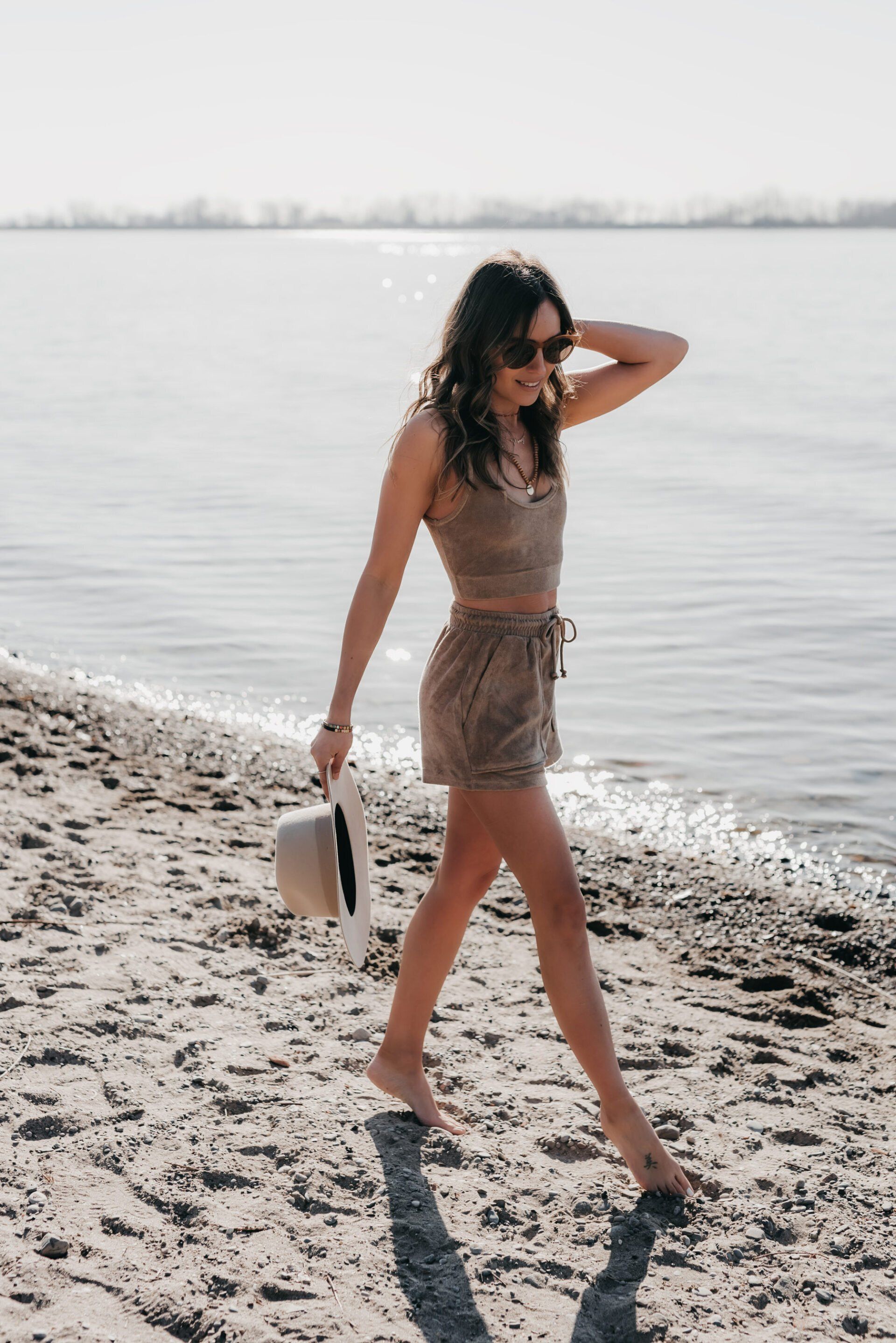 a woman wearing beige coords while walking on shore