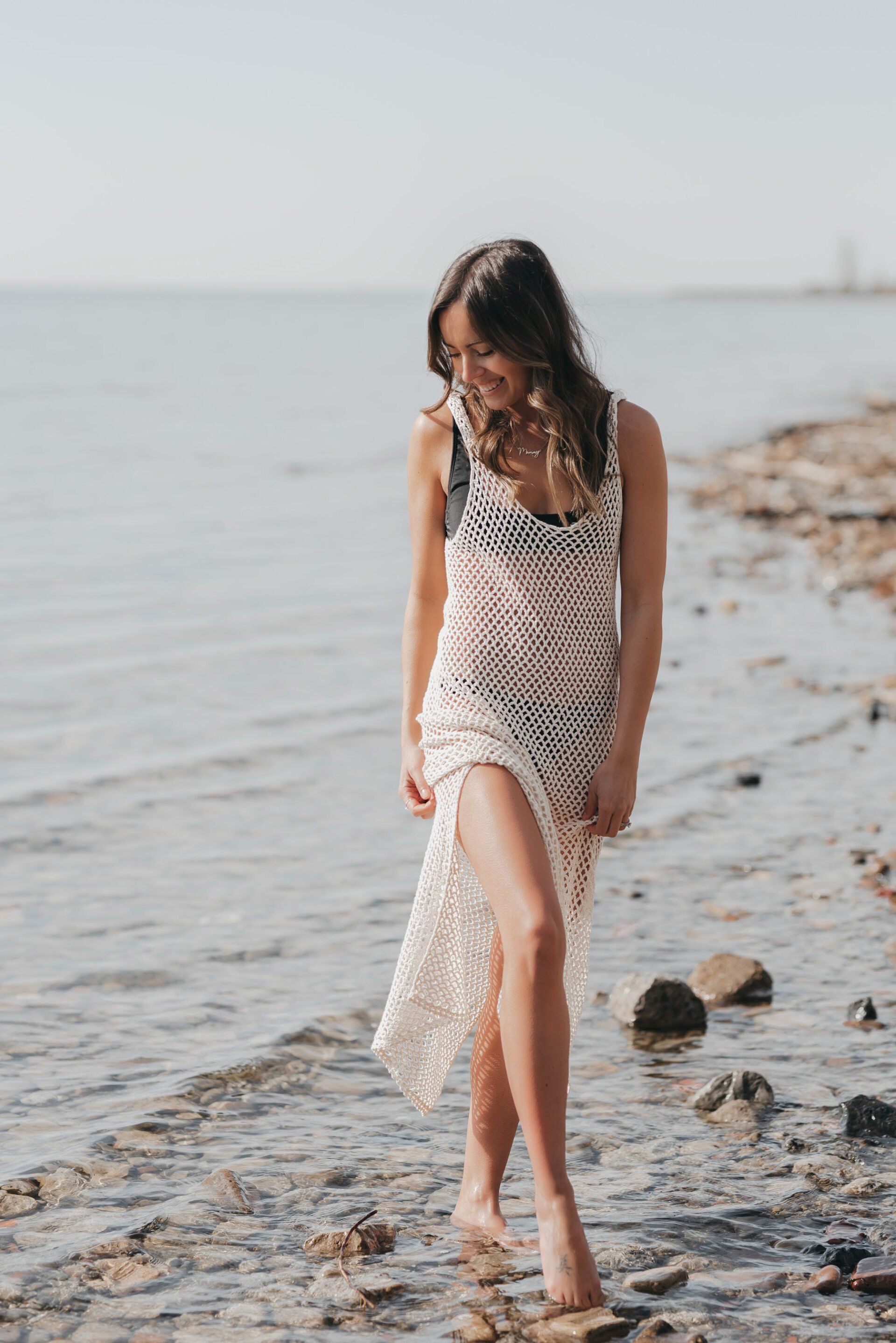 a woman walking on shore in a white mesh maxi dress