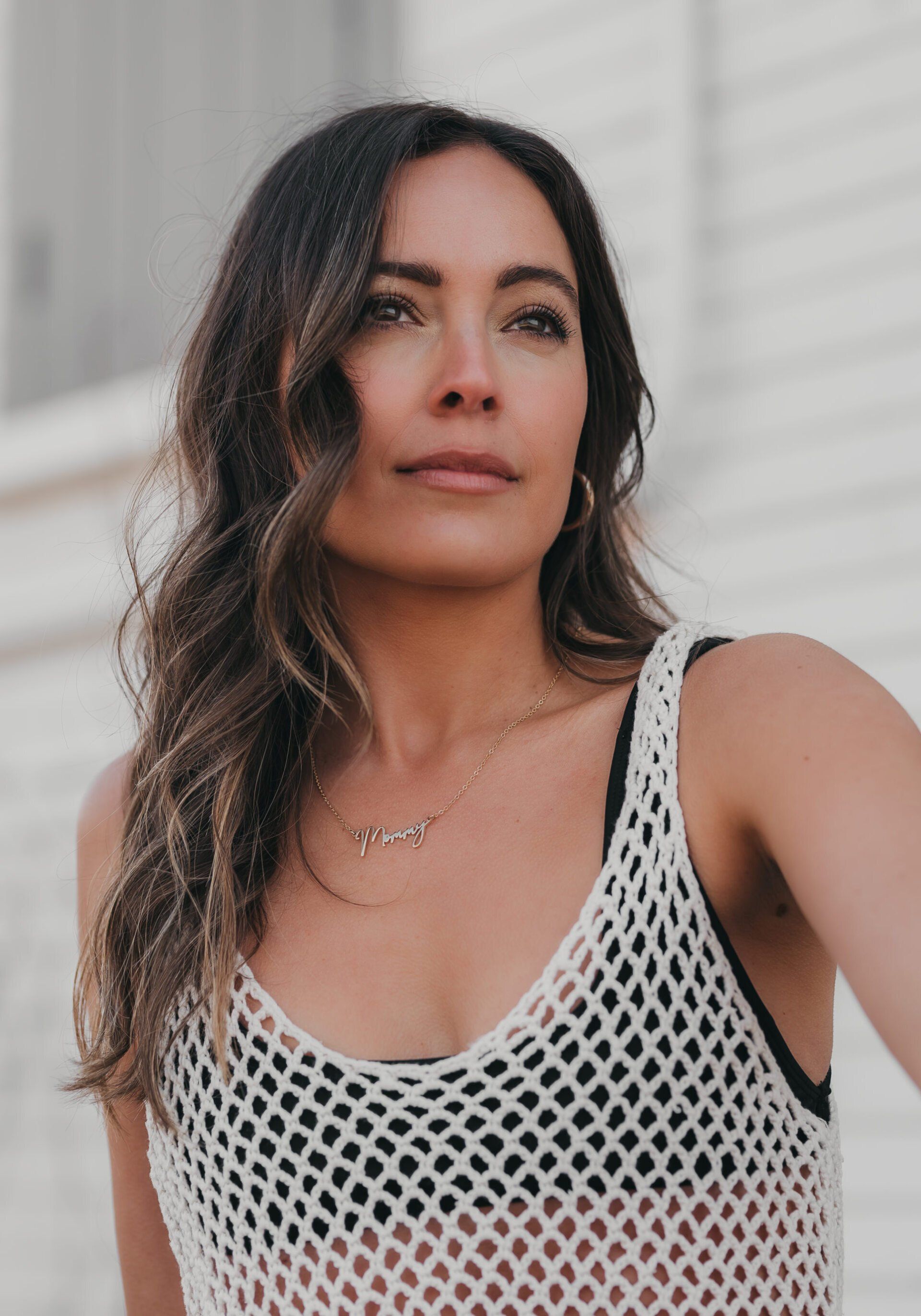 close up shot of a woman wearing a white mesh dress outside of a beach house