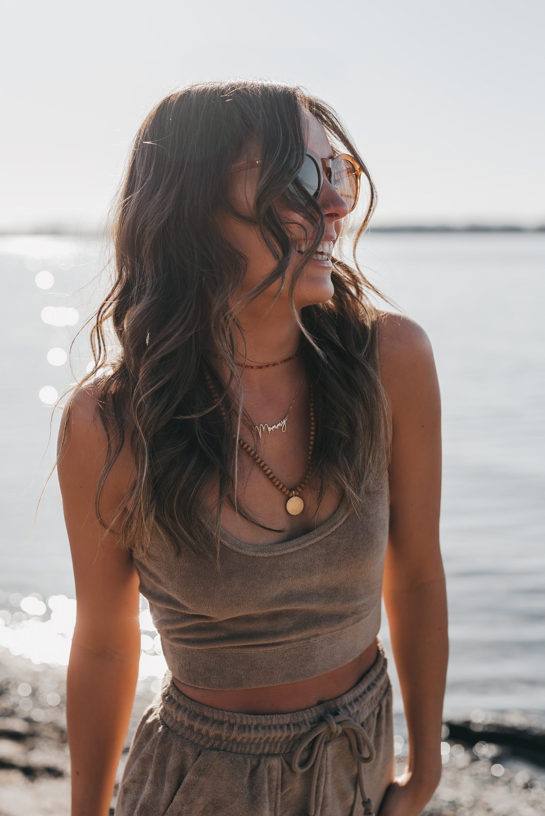 a woman at the beach wearing an earth tone boho outfit while looking sideways