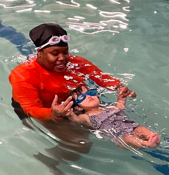 A man is teaching a little girl how to swim in a swimming pool.