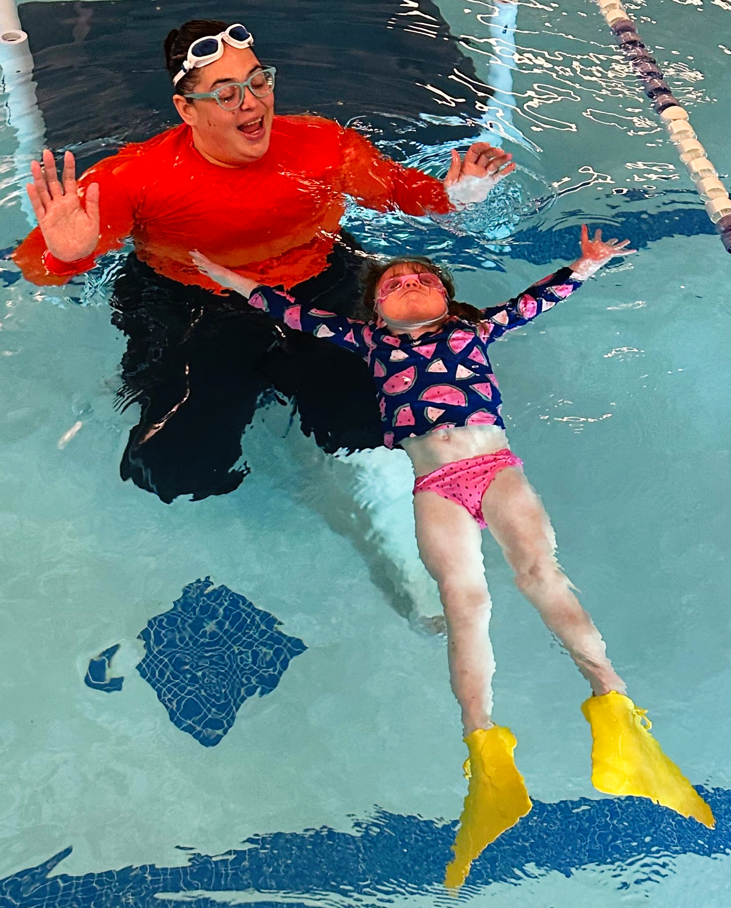 A young girl is swimming in a swimming pool.