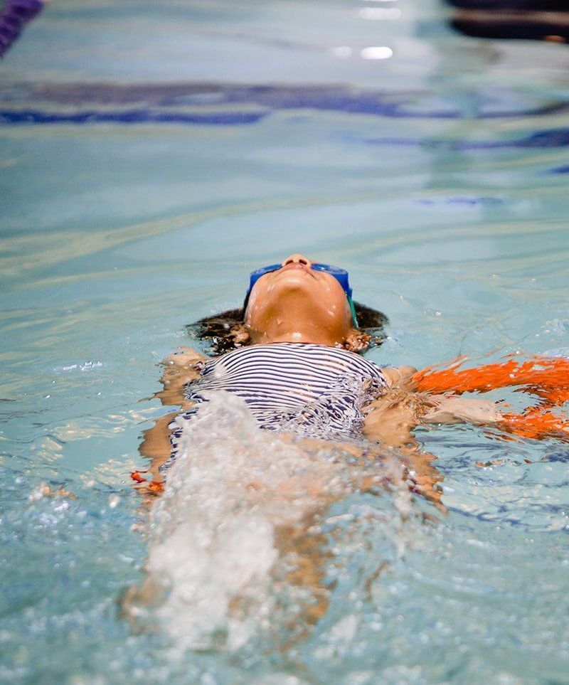 A young girl is swimming in a swimming pool.