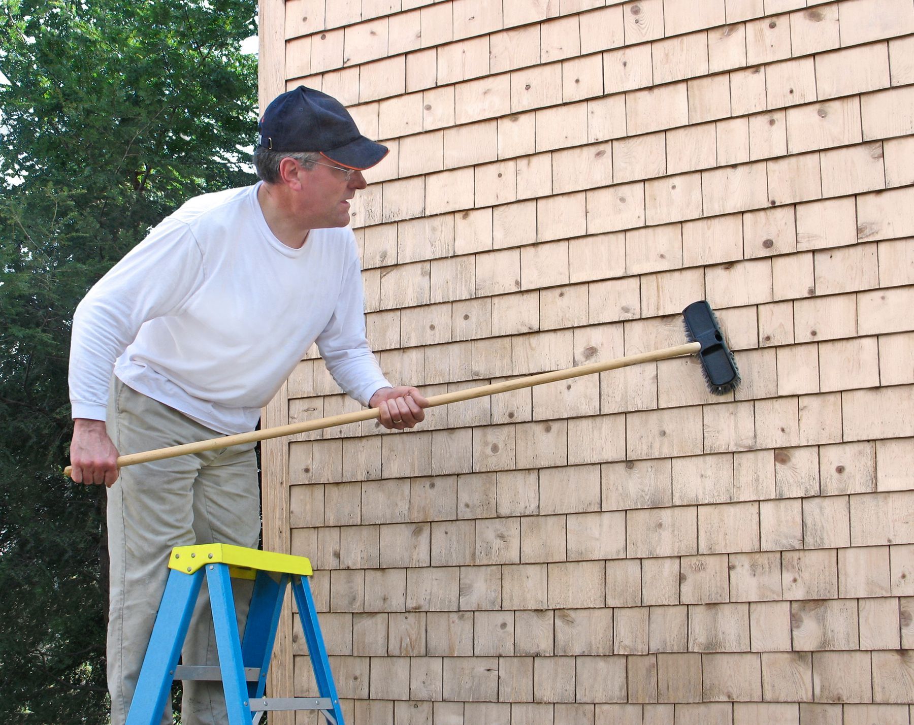 A man standing on a ladder holding a broom