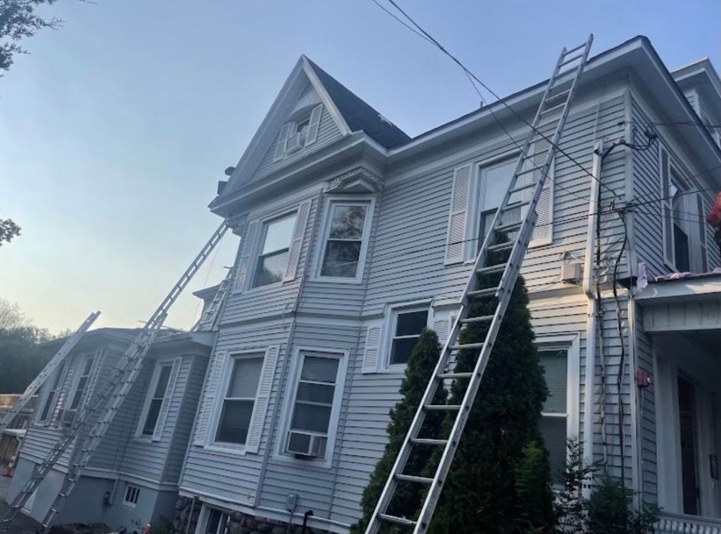 A group of people are working on the roof of a house.