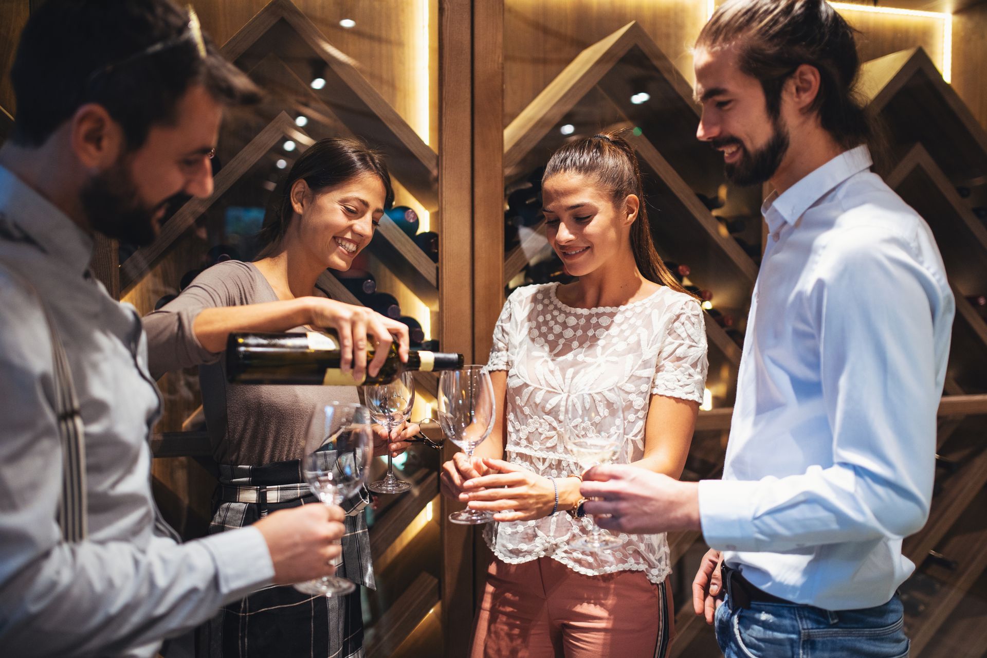 A group of people are drinking wine in a wine cellar.