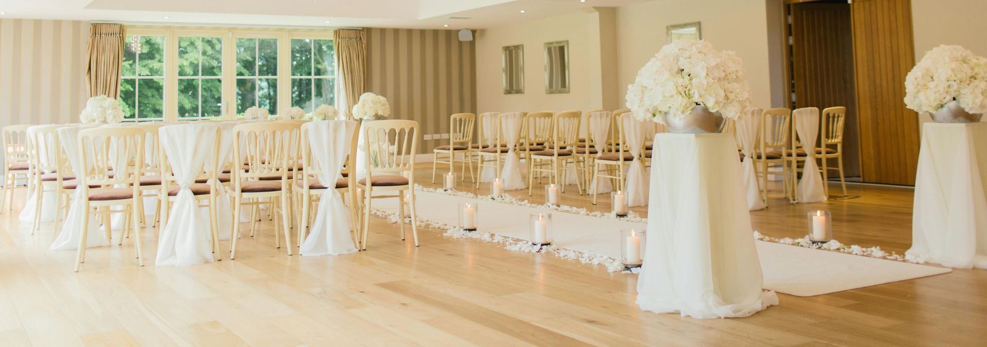 A room filled with chairs and candles for a wedding ceremony.
