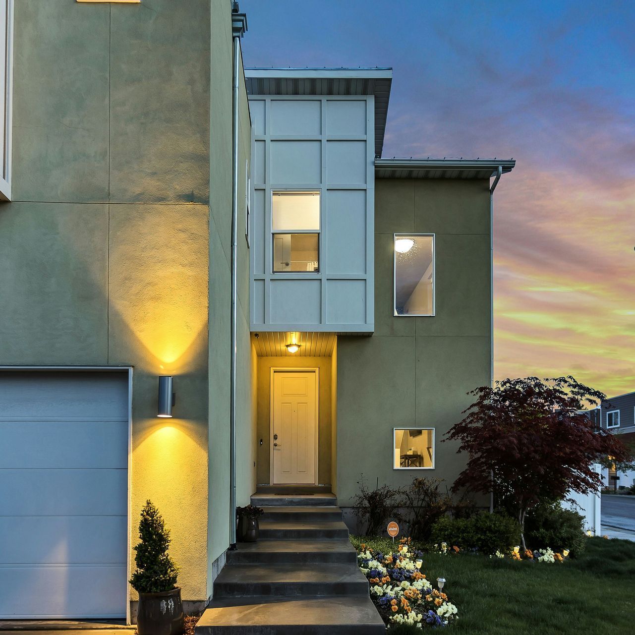 The front of a house with a garage and a sunset in the background.