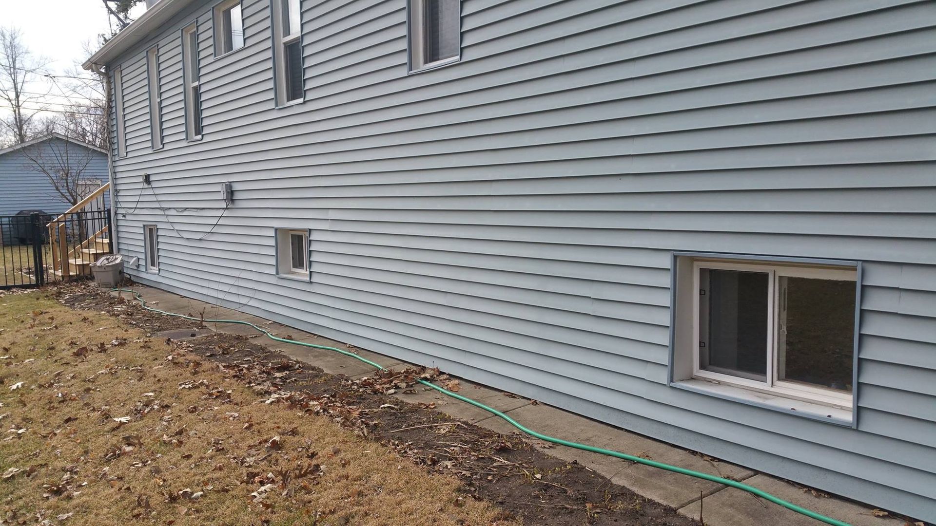A large blue house with a green hose in front of it.