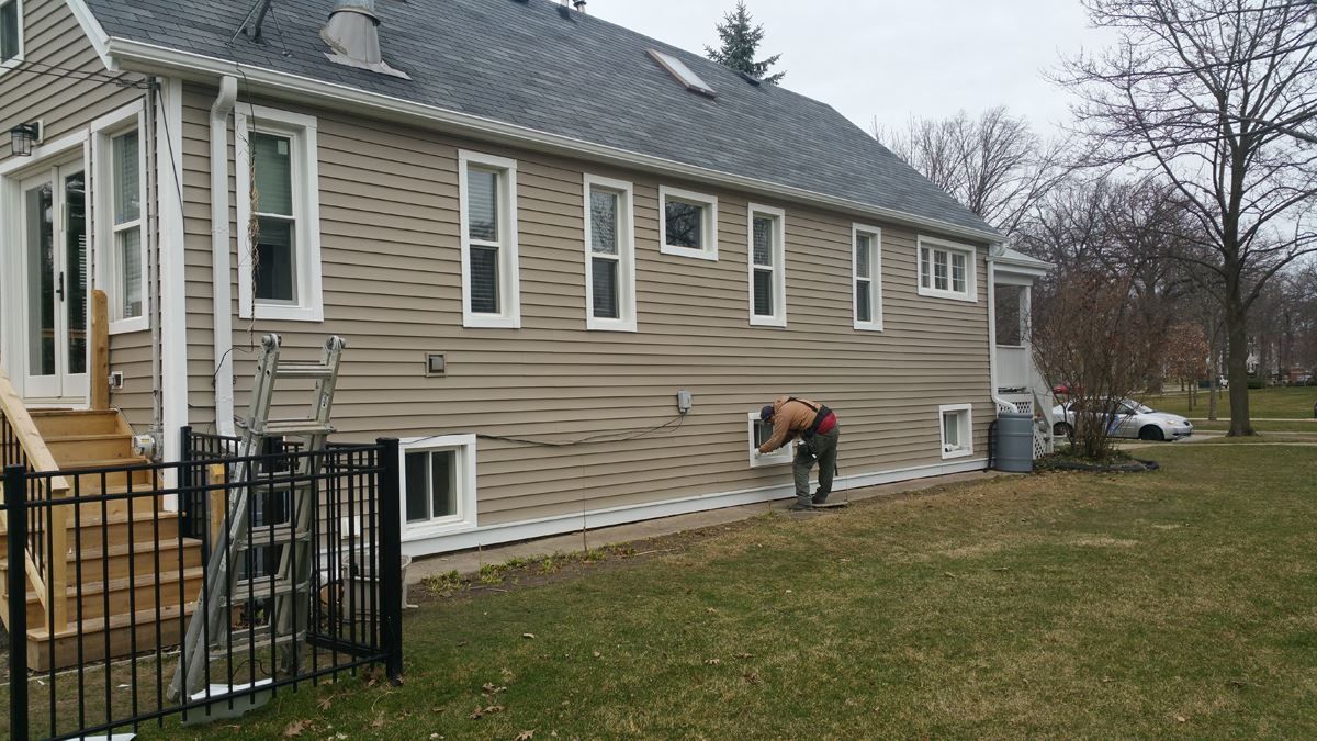 A man is working on the side of a house.