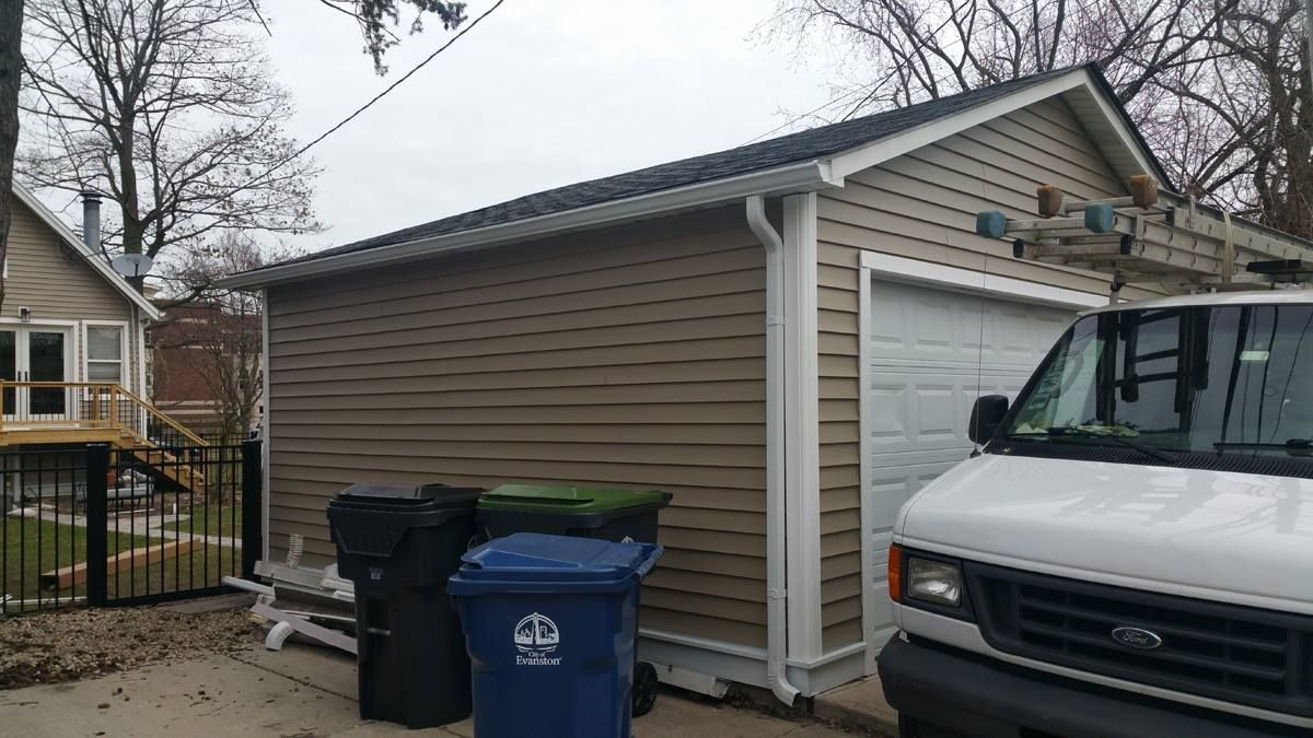 A white van is parked in front of a garage.
