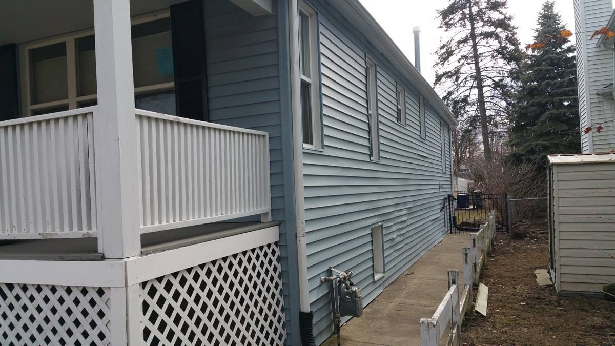 A blue house with a white porch and a white fence