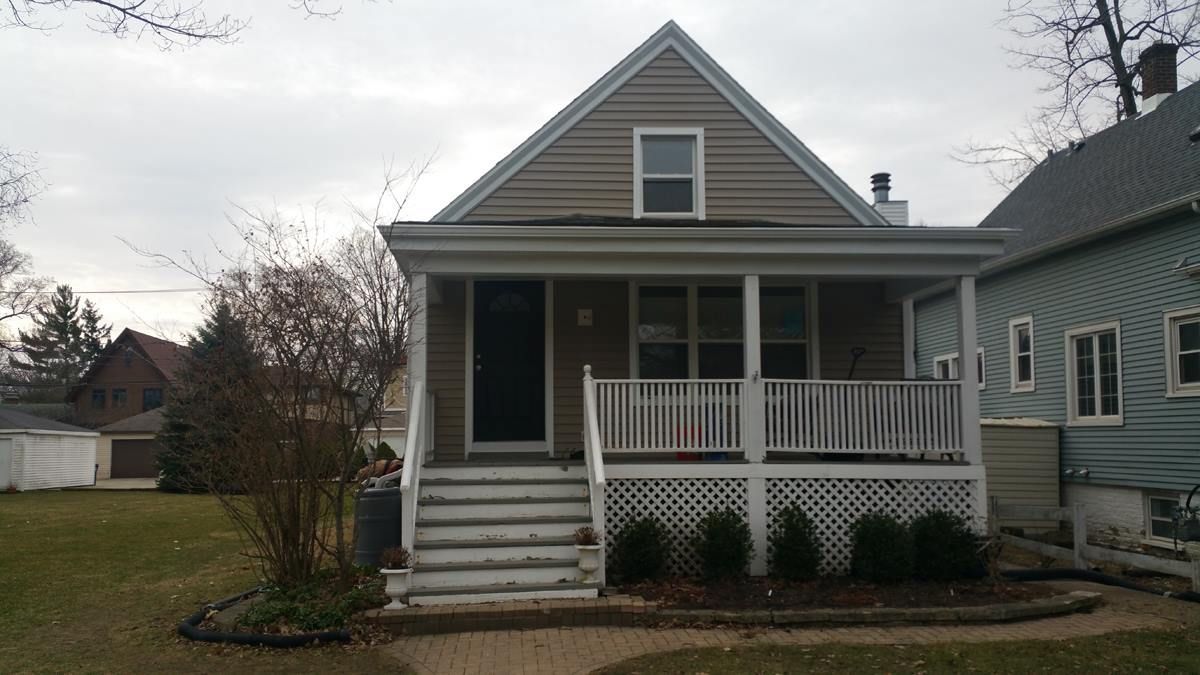 A house with a porch and stairs in front of it.