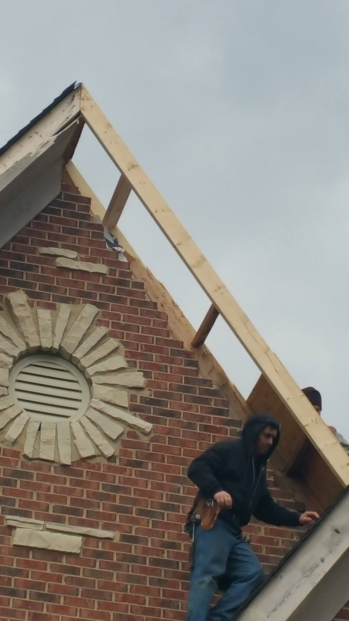 Two men are working on the roof of a brick building