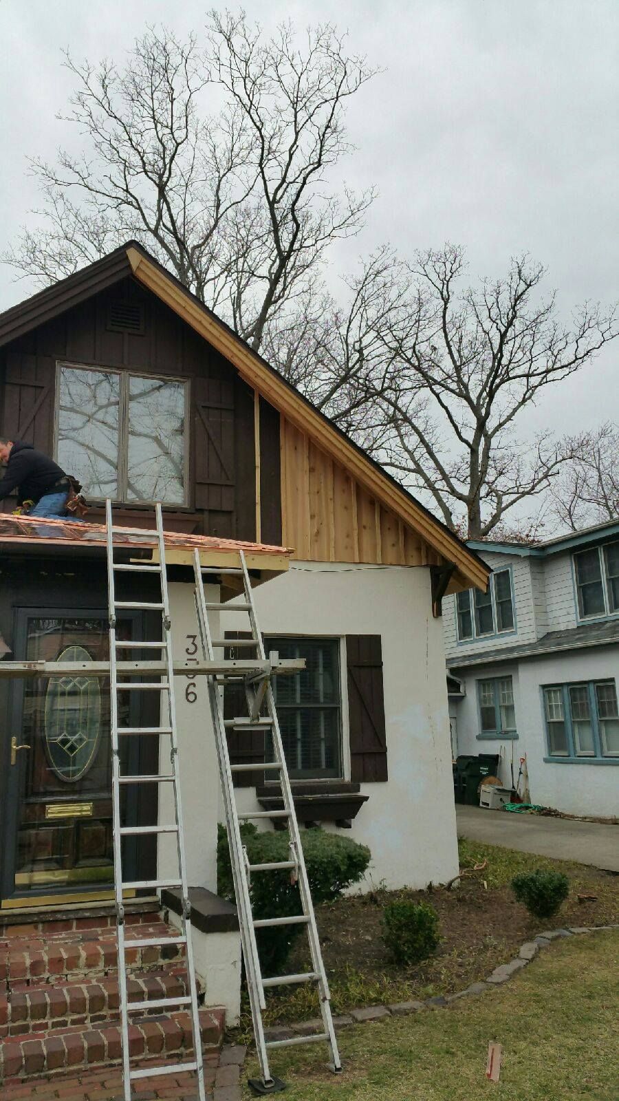 A man on a ladder is working on the roof of a house.